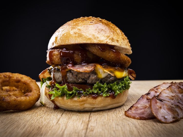 Burger mit frittierten Zwiebelringen, Bacon und BBQ