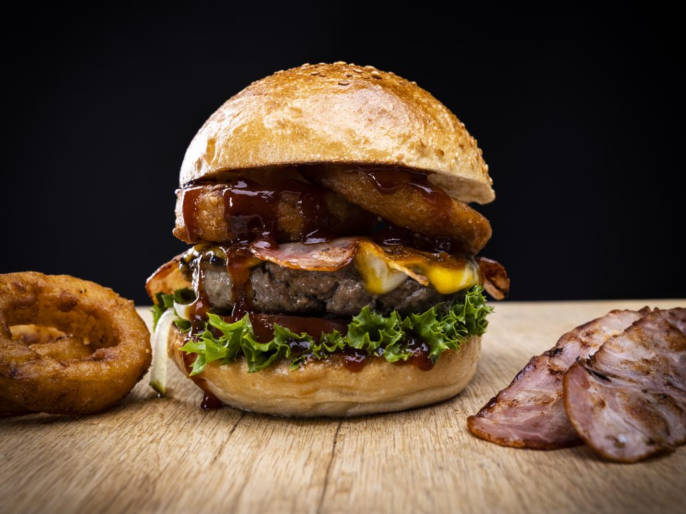 Burger mit frittierten Zwiebelringen, Bacon und BBQ