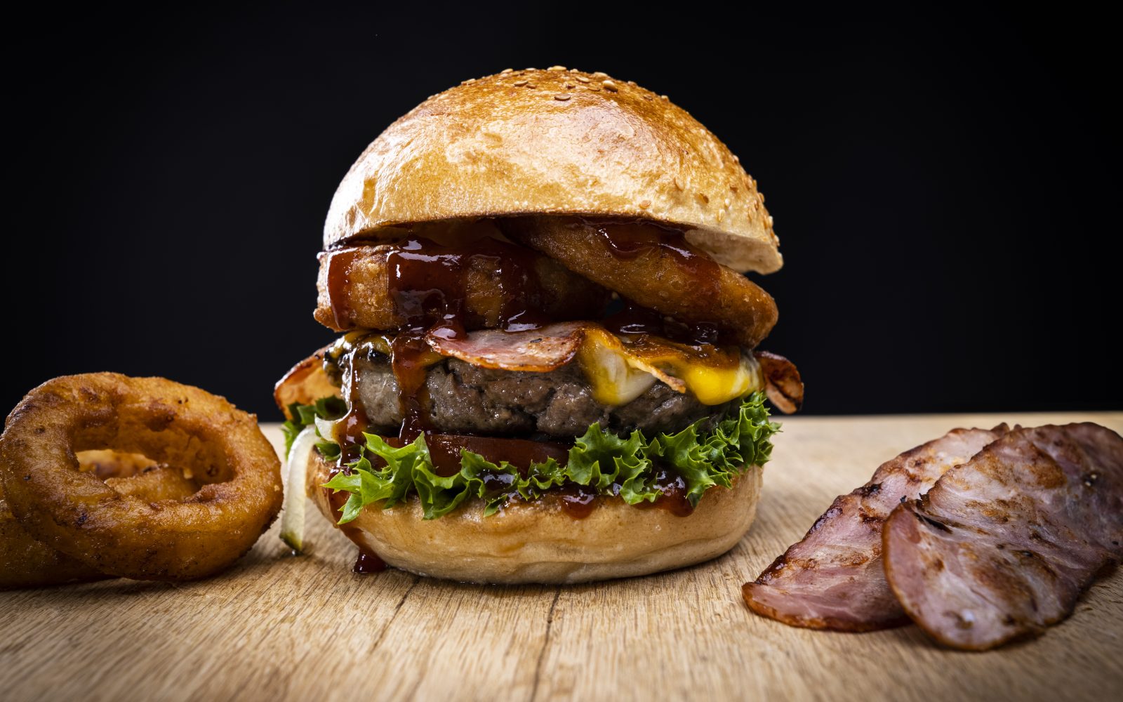Burger mit frittierten Zwiebelringen, Bacon und BBQ